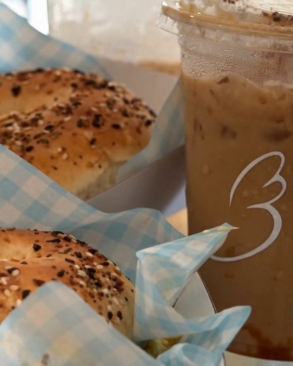 Everything bagels in blue gingham beside an iced coffee printed with the Baglory heart.